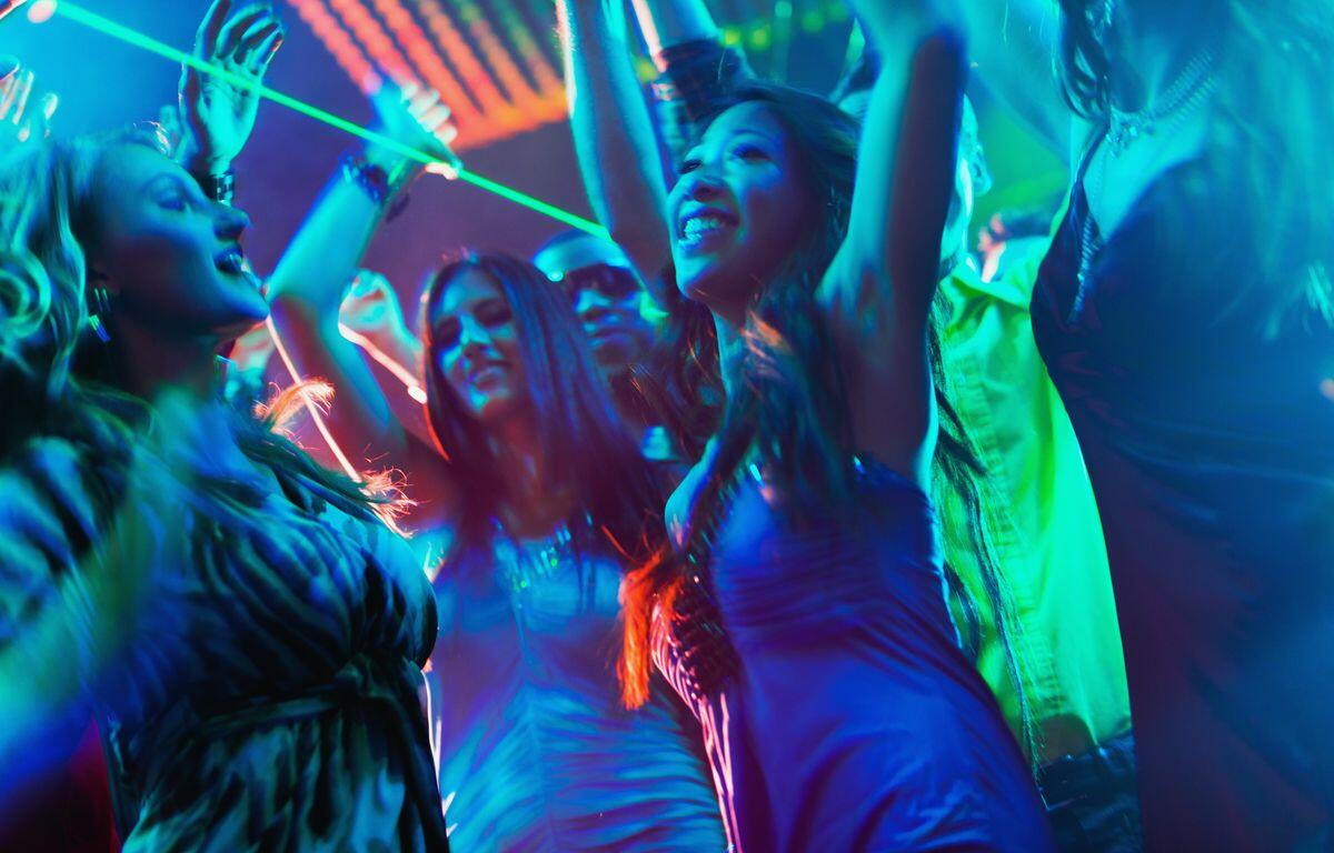 Party people dancing in disco or club