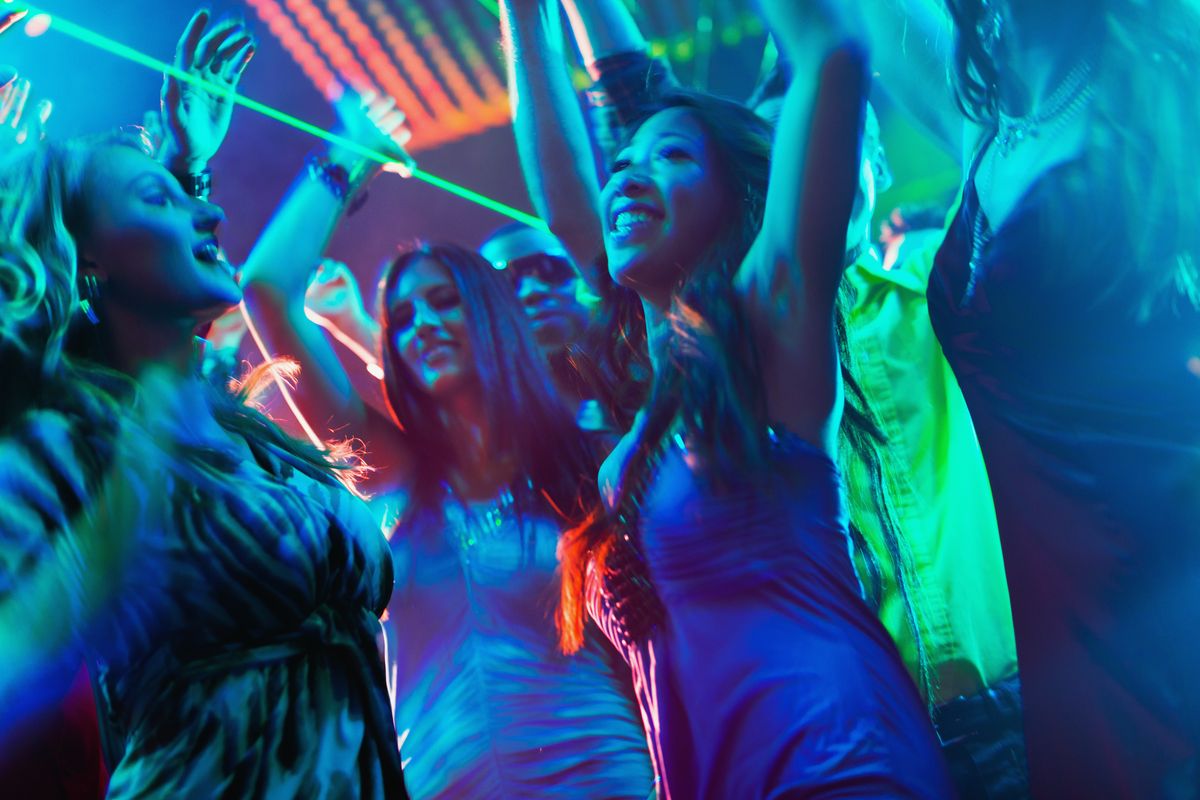 Party people dancing in disco or club