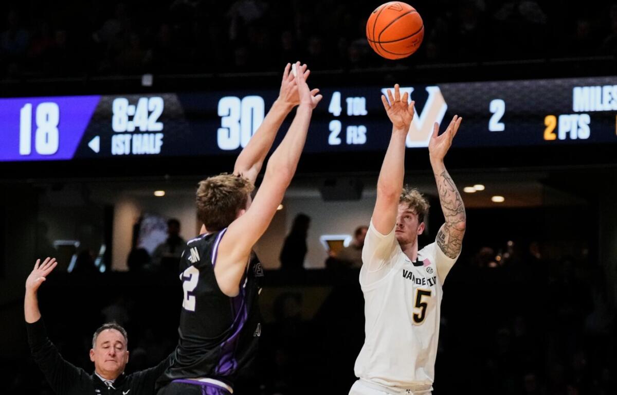 White jersey player #5 shoots the ball over a purple-jersey defender as the ball arcs upward.