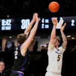 White jersey player #5 shoots the ball over a purple-jersey defender as the ball arcs upward.