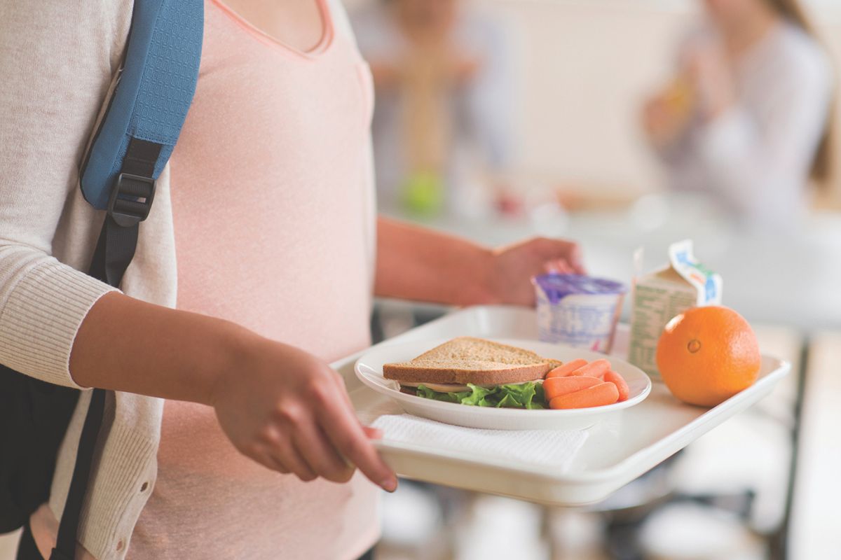 A student carrying a tray with food on it.