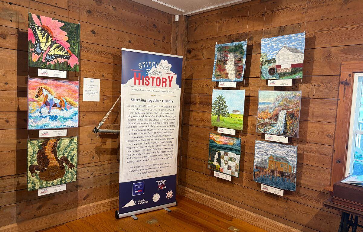 Stitching Together History sign with various quilt designs on the wall