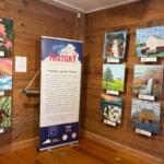 Stitching Together History sign with various quilt designs on the wall
