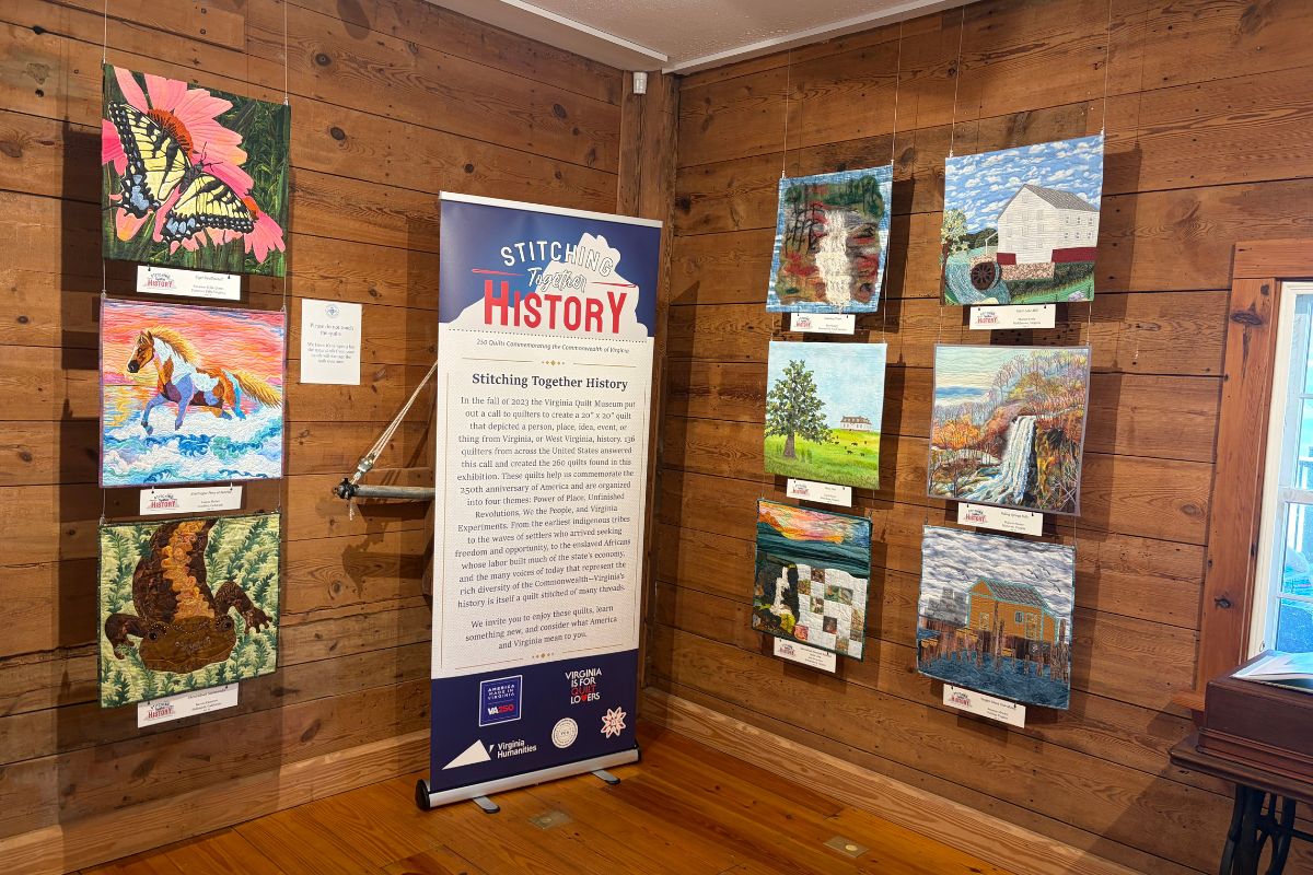 Stitching Together History sign with various quilt designs on the wall