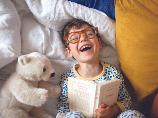 Young boy reading with polar bear stuffed animal