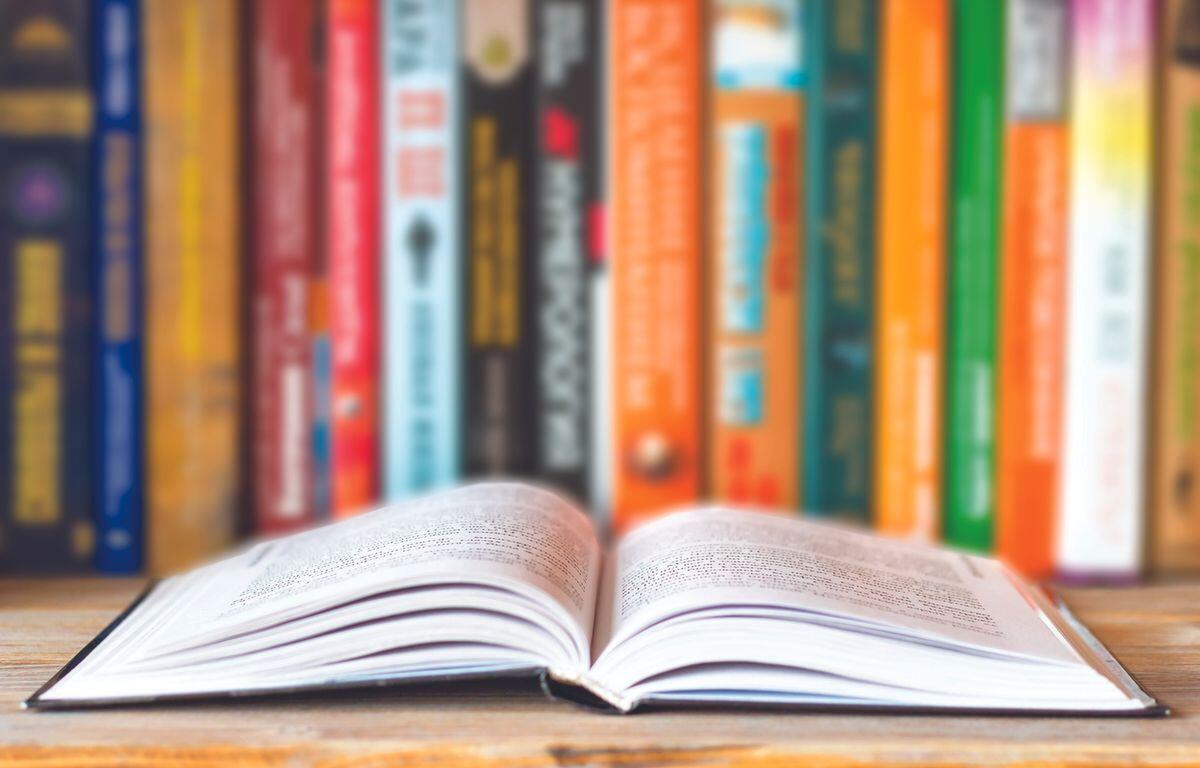 An open book with a shelf of books behind it