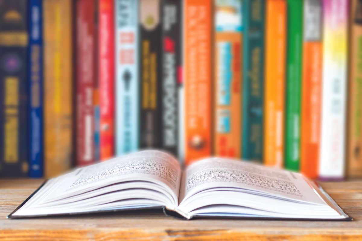 An open book with a shelf of books behind it