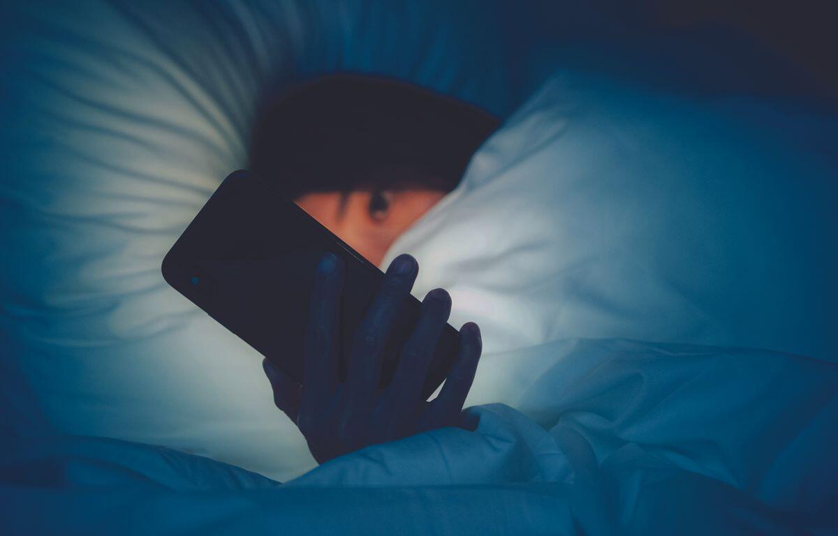Girl holding cell phone in bed