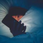 Girl holding cell phone in bed