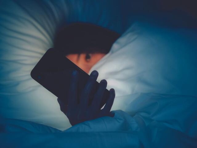 Girl holding cell phone in bed