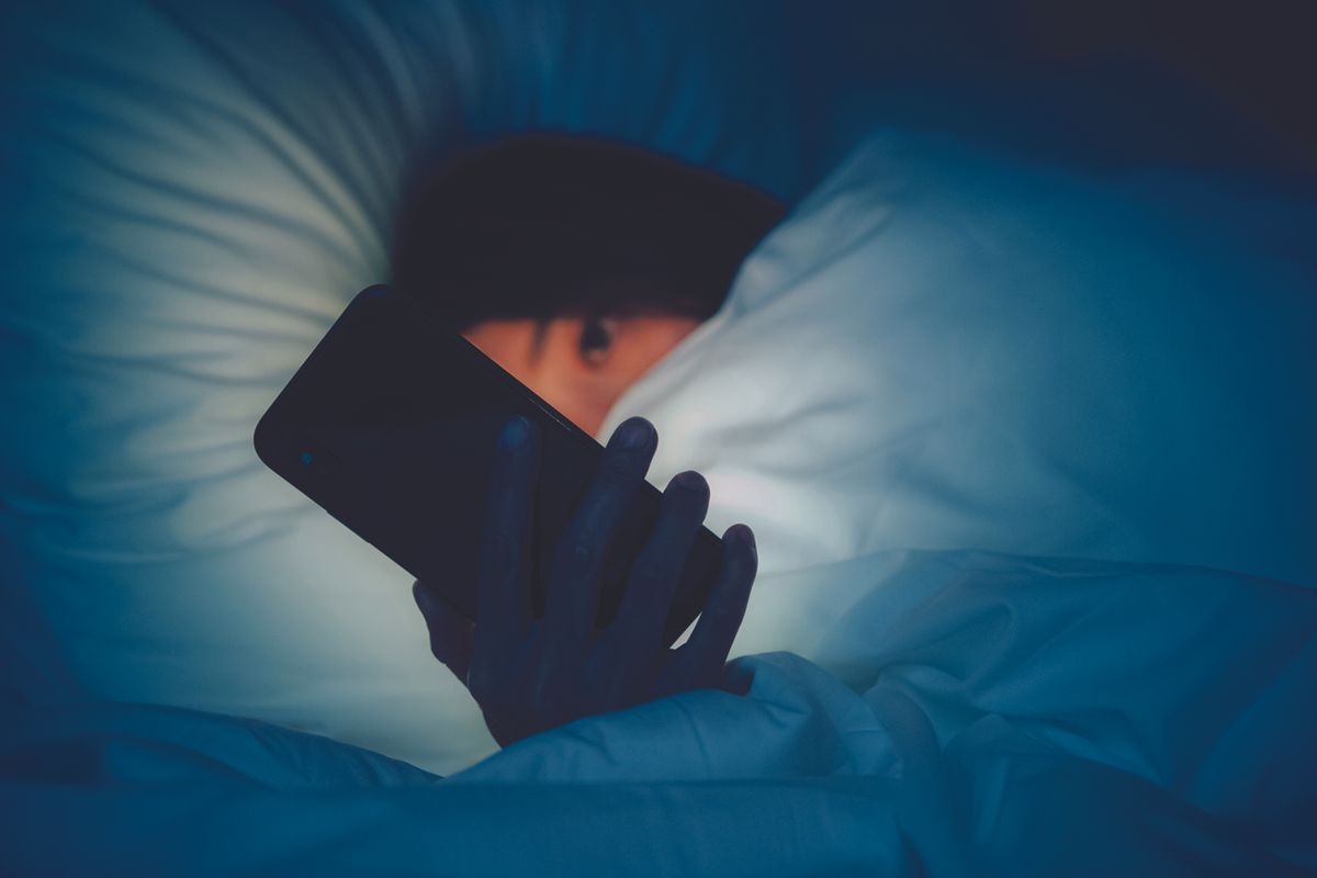Girl holding cell phone in bed