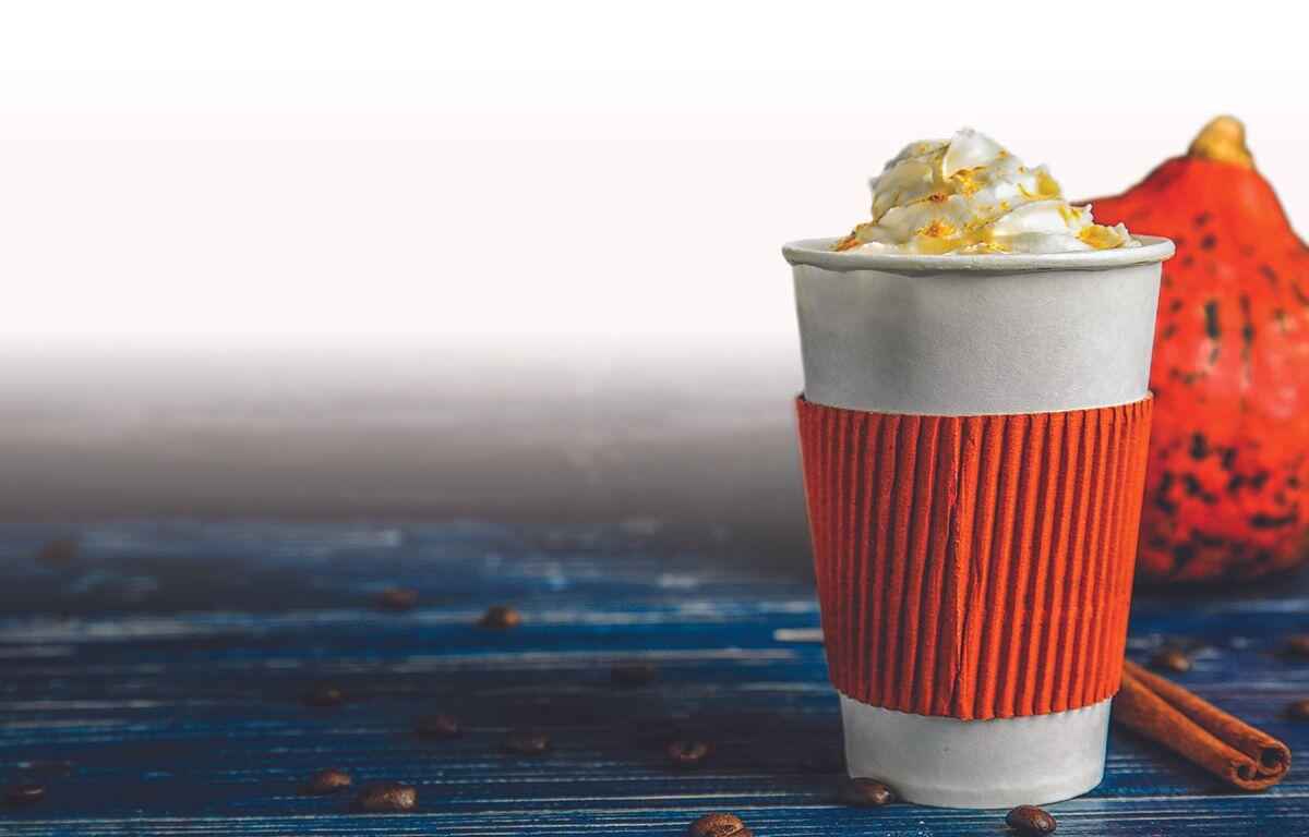 Latte with a cinnamon stick and pumpkin in the background