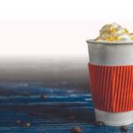 Latte with a cinnamon stick and pumpkin in the background